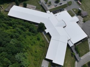 Overhead drone image of the new white TPO roofing system installed on Freedom Trail School in Newland, NC, highlighting the seamless commercial flat roof installation.
